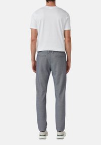 Grijze op maat gemaakte broek met twee achterzakken, een gladde textuur, samen met een eenvoudig wit T-shirt en sportieve schoenen.