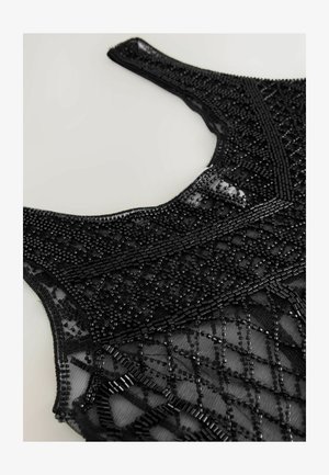 Černý zdobený top s propracovaným korálkováním, strukturovanou síťovinou a geometrickým vzorem podél výstřihu a těla.