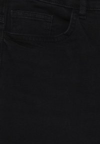 Tela de mezclilla negra con textura suave, que cuenta con un solo bolsillo trasero y trabillas para el cinturón. Diseño simple y uniforme sin patrones ni adornos.