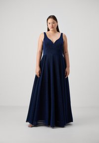 Navy blue pitkä helmainen mekko, jossa on istuva yläosa, leveät hihnat ja V-pääntie. Mekossa on teksturoitu kangas ja virtaava hame.