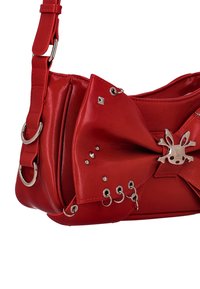Röd syntetisk handväska med stor rosettdetalj, silverfärgade metalldetaljer och dekorativa nitar. Utrustad med axelrem och dragkedja.
