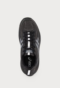 Black athletic shoe with a textured upper, reflective accents, and a cushioned sole. Features a central white stripe and logo on the insole.