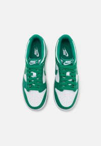 Grønne og hvite Nike-sneakers med perforert tå, snøring, polstret krage og hvit gummisåle. Merking på tungen og sidene.
