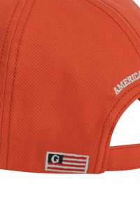 Cappello arancione in tessuto testurizzato, con cuciture bianche e un logo ricamato. Cinturino regolabile sul retro con un piccolo design a bandiera.