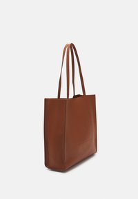 Sac fourre-tout en cuir marron avec deux longues anses, une forme structurée et une poche avant. Texture lisse et design minimaliste.