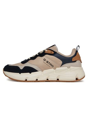 Zapatilla de mezclilla G-Star Raw en beige y negro con suela blanca gruesa, acento en el talón color marrón claro, cierre de cordones en la parte delantera y tirador en el talón.