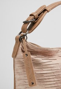 Borsa a mano in pelle color cuoio con strisce verticali testurizzate, una fibbia metallica e una targhetta rettangolare con la scritta in rilievo "first and second".