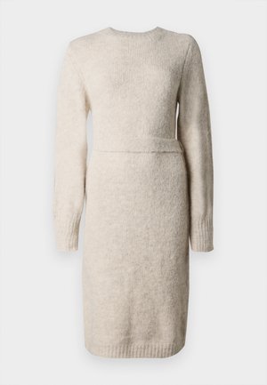 Gebreide beige jurk met lange mouwen, ronde halslijn en een gestructureerde afwerking. Passend in de taille met een accentband, knielange zoom.