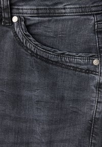 Jean en denim gris foncé avec une poche avant ornée de détails de couture et un bouton argenté. Texture subtile sur l'ensemble du tissu.