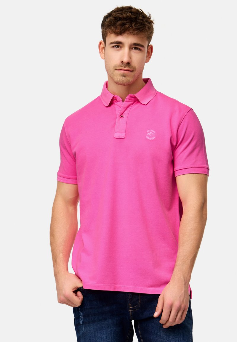 Rosa polo skjorte med korte ermer, krage og en liten hvit logo på brystet. Myk stoffkvalitet, uformell design, kombinert med mørk denim jeans.