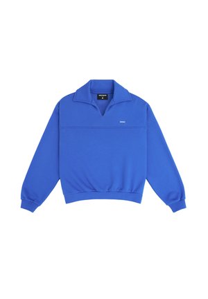 Felpa blu con collo alto, polsini e orlo a coste. Presenta una cucitura orizzontale e un piccolo logo sul petto.
