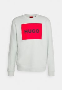 Felpa grigia chiaro con collo rotondo e polsini a coste, caratterizzata da una grafica rettangolare rosa audace con la parola "HUGO" in nero.