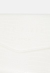 Clutch de piel sintética blanca tipo cocodrilo con el logo grabado "TED BAKER LONDON", cierre angular en la solapa y detalles cosidos a lo largo de los bordes.