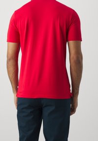 Červené tričko s krátkým rukávem, hladkou a lehkou texturou, kulatým výstřihem a těsným střihem, kombinované s námořnickými kalhotami.