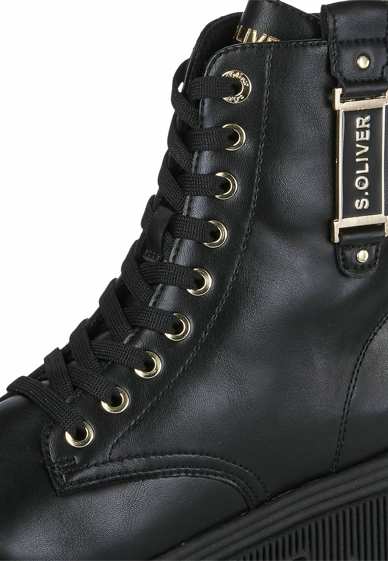 Schwarze Leder-Ankle-Boots mit goldfarbenen Ösen, schwarzen Schnürsenkeln und einem markierten goldenen Akzent an der Seite. Texturierte Sohle für zusätzlichen Halt.