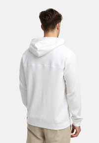 Witte hooded sweatshirt met geribbelde textuur, met een effen bovenstuk. Lange mouwen en een casual pasvorm. Eenvoudig ontwerp zonder zichtbare logo's.