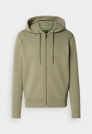 Olive green zip-up hoodie made of soft fabric. Features a drawstring hood, ribbed cuffs, and a small logo on the chest.
