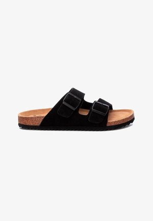 Sandalias deslizantes de ante negro con dos hebillas ajustables, planta de corcho, suela texturizada negra y superficie interior lisa.