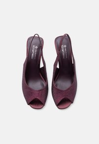 Ζευγάρι σκούρα μοβ πέδιλα με ανοιχτή μύτη και λουρί στο πίσω μέρος, διακοσμημένα με μικρές στρας, χαρακτηρισμένα ως vegan με μαλακή αφράτη επένδυση.