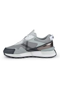 Zapatillas grises y negras con tejido de malla, detalles de ante, cordones blancos y un detalle del talón en bronce metálico. Suela de goma con un dibujo texturizado.
