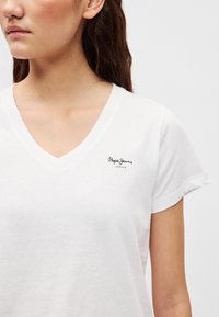 Λευκό βαμβακερό μπλουζάκι με V-λαιμόκοψη και κοντά μανίκια. Διαθέτει μικρό μαύρο λογότυπο "Pepe Jeans London" στην αριστερή πλευρά του στήθους. Μαλακή υφή.