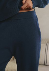 Navy blue sweatpants with a ribbed waistband, made of soft fabric. Features a smooth texture and subtle stitching detail along seams.