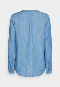 Långärmad denimskjorta i ljusblått, med kragefri design, lätt textur och rundad nederkant. Inkluderar knäppta manschetter.