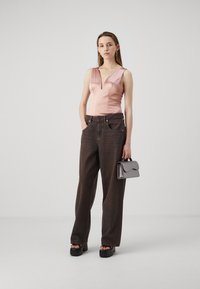 Szatén rózsaszín bodysuit mély dekoltázzsal, laza sötét farmernadrággal párosítva. Kiegészítve egy kis szürke kézitáskával és platform szandálokkal.
