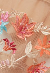 Geborduurd gaasstof heeft een bloemenpatroon in roze, oranje en blauw op een perzikkleurige achtergrond, met ingewikkelde details en een zachte textuur.