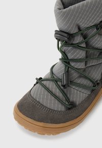 Stivale grigio in tessuto e suede con lacci elastici, caratterizzato da accenti verdi. Punta arrotondata e suola testurizzata progettata per aderenza e stabilità.