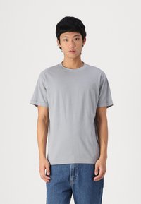 Gray short-sleeve t-shirt in soft cotton fabric. Features a round neckline and a relaxed fit, paired with blue denim jeans.