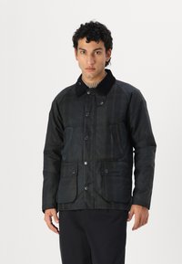 Dark plaid jacket with a black corduroy collar, front snap closure, two large patch pockets, and waterproof fabric. Textured design.