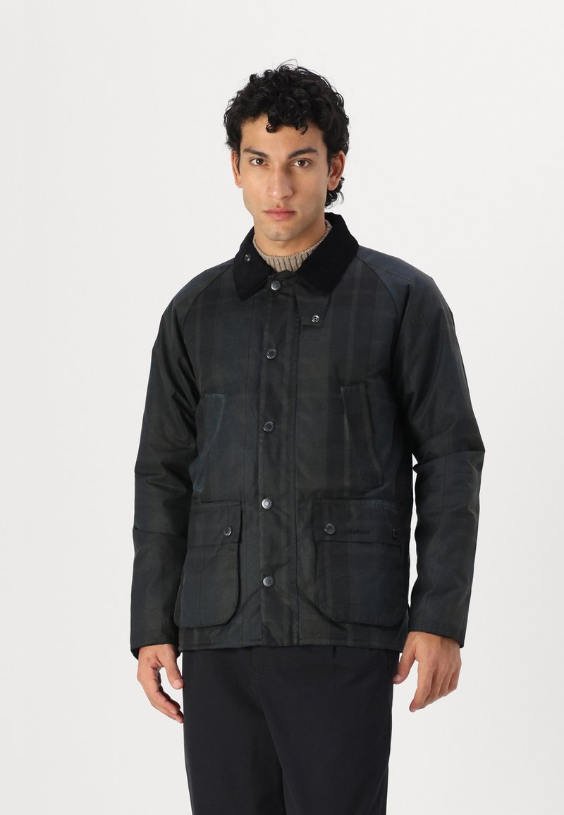 Dark plaid jacket with a black corduroy collar, front snap closure, two large patch pockets, and waterproof fabric. Textured design.