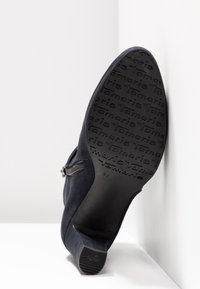 Bottine en daim bleu marine avec talon bloc, fermeture éclair latérale et semelle ornée du logo « Tamaris » et taille 37.