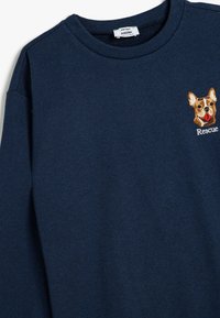 Sudadera de color azul marino en suave algodón con un destacado diseño de cabeza de perro bordado y el texto "Rescue" en el pecho.