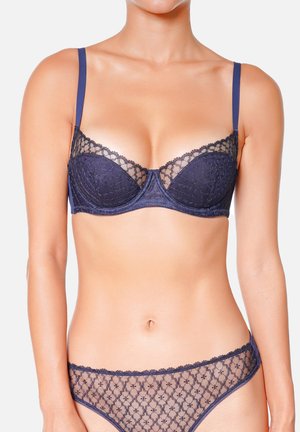 Ensemble de lingerie bleu marine comprenant un soutien-gorge push-up bordé de dentelle et un string coordonné en tissu transparent avec des motifs géométriques et des bretelles ajustables.