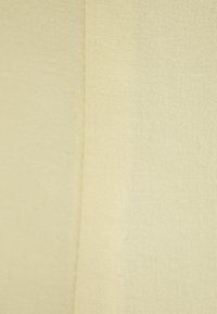 Jasno beżowa tkanina o gładkiej fakturze, z delikatnym połyskiem i wyraźnym przeszyciem wzdłuż krawędzi, co tworzy czysty, dopasowany wygląd.