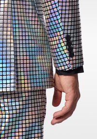 Holografischer Anzug mit metallischen Quadraten in verschiedenen Farben. Ausgestattet mit vier schwarzen Knöpfen am Handgelenk und einer eleganten, reflektierenden Textur.