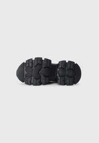 Black rubber shoe outsole with deep treads and a reinforced midsection, featuring a textured pattern for enhanced grip and stability.