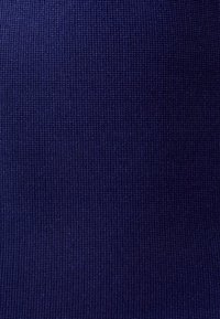 Námořnická modrá tkanina s texturovaným, tkaným vzorem, který obsahuje žebrovaný design vhodný pro oděvy nebo čalounění.