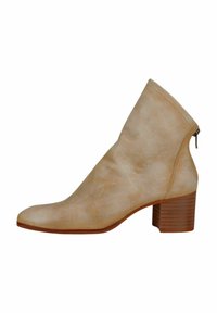 Bottine beige avec une texture lisse, bout arrondi, talon bloc de hauteur intermédiaire et détail de fermeture éclair sur le côté. Fabriquée en cuir doux.