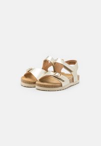 Guldmetalliska sandaler med två breda remmar, spänne, korkfotbädd och beige gummisula. Avslappnad design och öppen tå-stil.