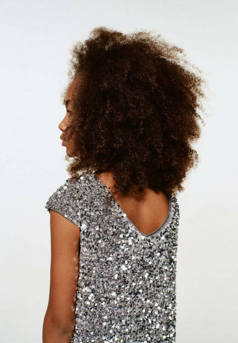 Rochie argintie cu paiete, decoltată în V și cu mâneci scurte, având o suprafață texturată. Spatele este expus, cu un tiv gri neted.