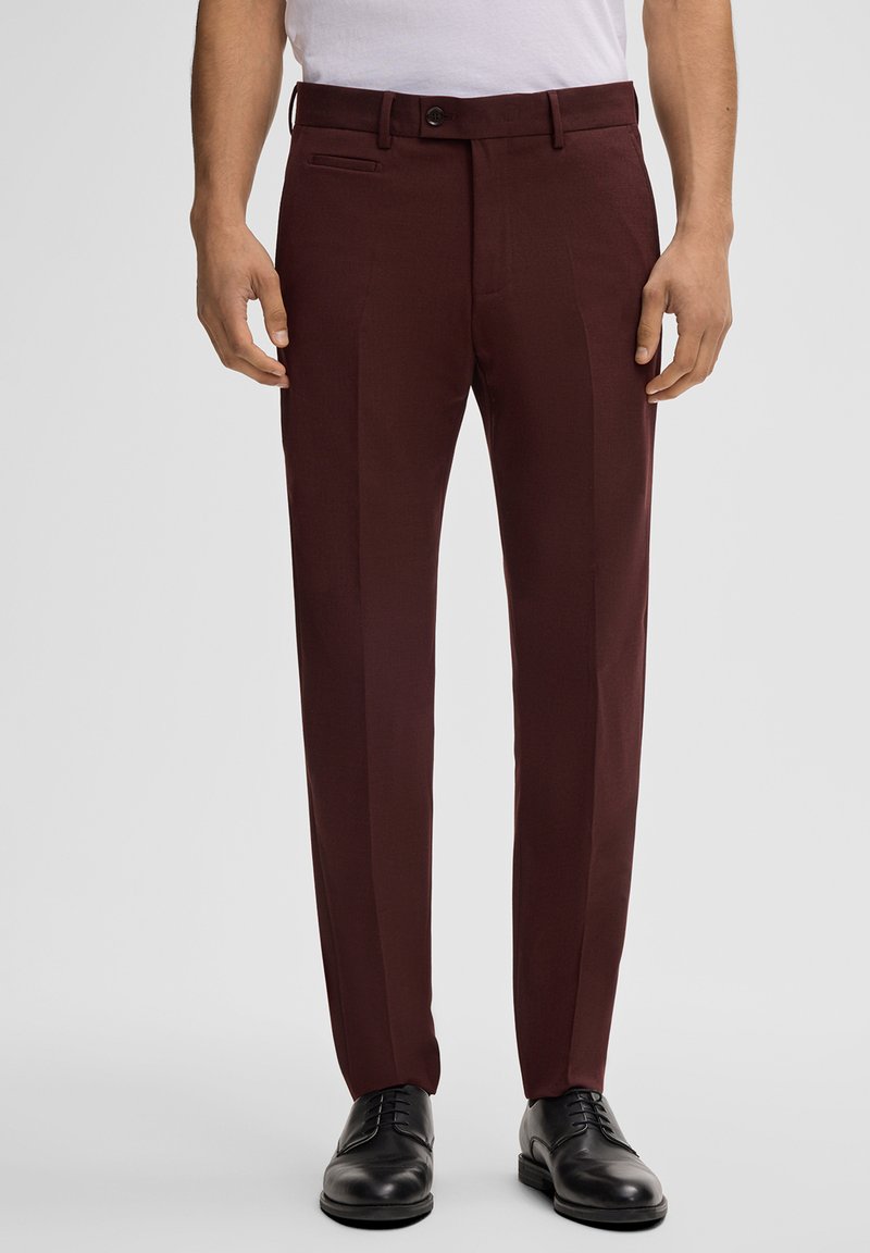 Bordeaux op maat gemaakte broek met een slank ontwerp, voorzien van een platte voorkant, zijzakken en een gladde textuur. Gepaard met zwarte nette schoenen.
