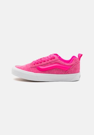 Zapatillas rosas con un upper texturizado, acentos lisos en contraste, suela de goma blanca y cordones a juego, con un logo en el talón.