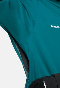 TÜRQUOISE wasserfeste Jacke mit Reißverschlussbelüftungen, grauer Innenauskleidung und schwarzen Akzenten. Mit MAMMUT-Logo auf der oberen linken Seite.