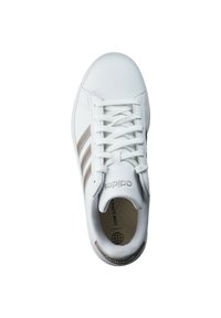 Witte sneakers met drie bruine strepen, een gladde leren buitenkant, ronde neus en platte veters. Het interieur heeft een patroon op de binnenzool.
