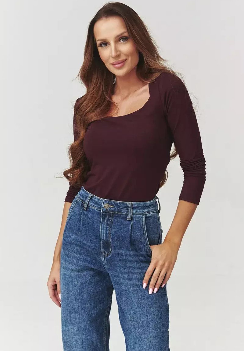 Burgundowa bluzka z długim rękawem i kwadratowym dekoltem, w połączeniu z niebieskimi dżinsami o wysokim stanie. Gładki materiał z dopasowanym krojem.