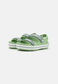 Vihreät sandaalit, joissa on harmaa hihna, valmistettu synteettisestä materiaalista. Ominaisuuksiin kuuluu teksturoitu pohja, avoin takapuoli ja valko-rajaista pohjaa.