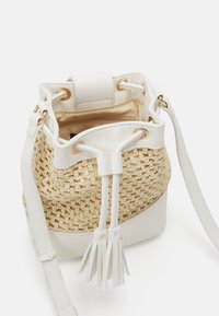 Borsa a secchiello in paglia intrecciata con rifiniture in ecopelle bianca, dotata di accessori dorati, chiusura con cordoncino e pompon decorativi.